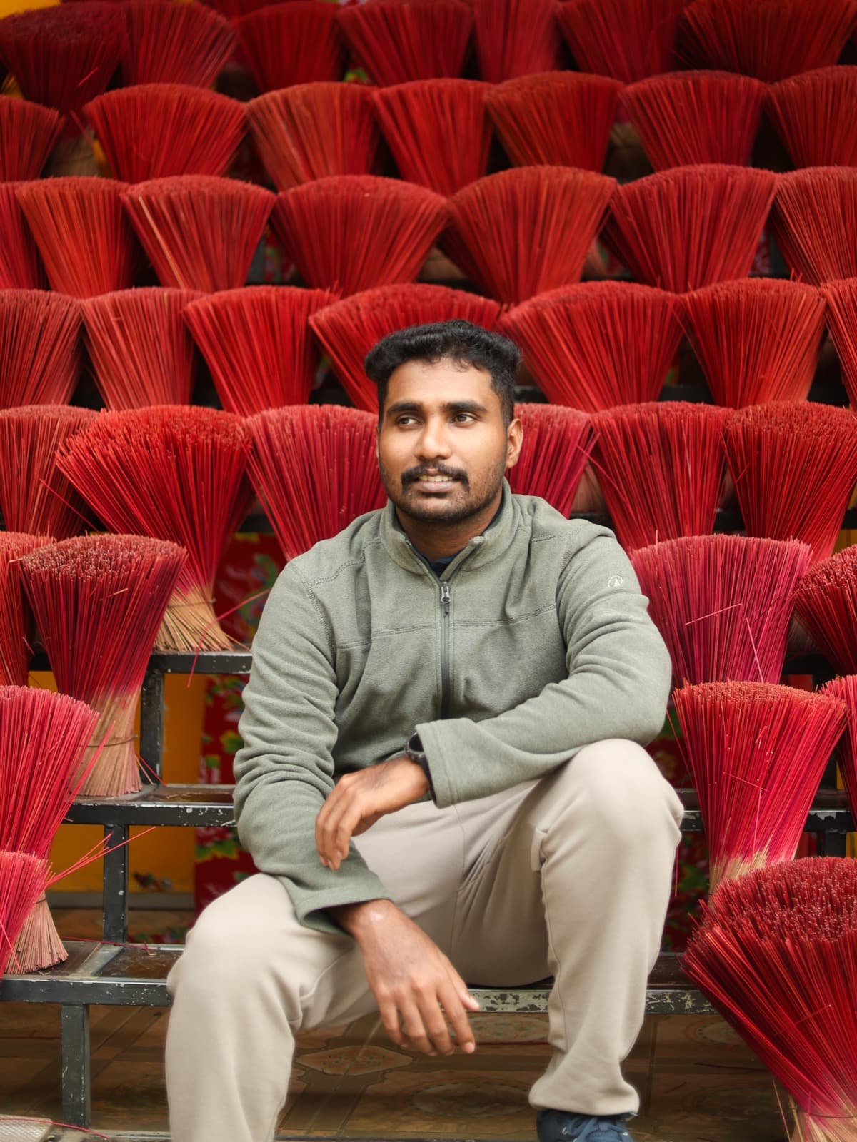 Aromal S sitting in front of rows of red incense bundles